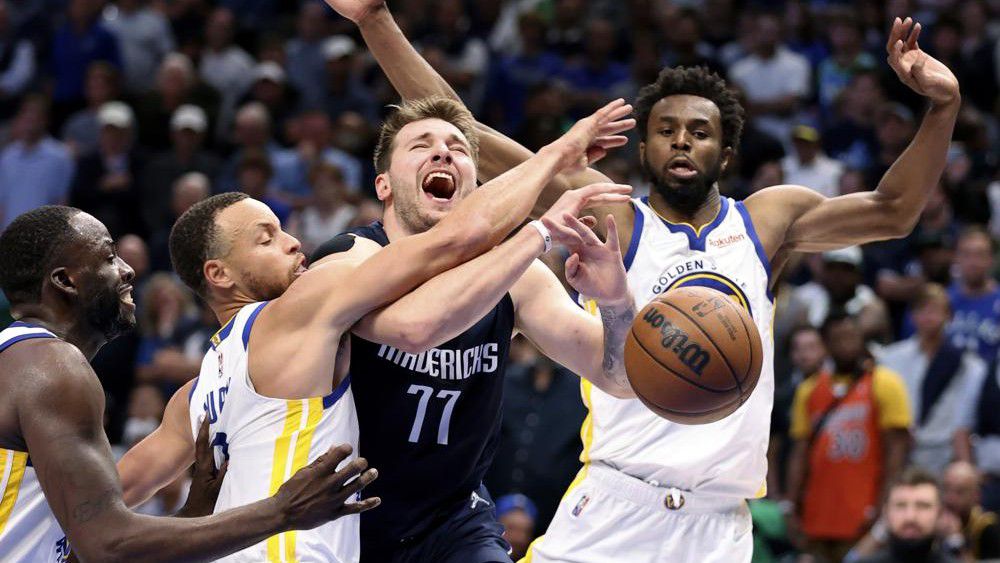 Dallas Mavericks' Luka Doncic is fouled by Stephen Curry as Draymond Green and Andrew Wiggins watch during the second half of Game 3 of the NBA basketball playoffs Western Conference finals, Sunday, May 22, 2022, in Dallas. (Scott Strazzante/San Francisco Chronicle via AP)