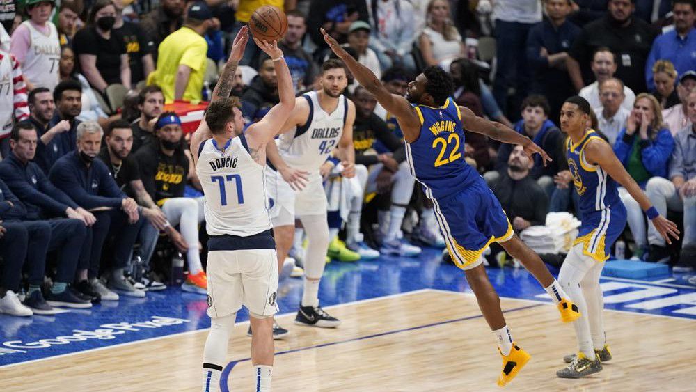 Dallas Mavericks guard Luka Doncic shoots a 3-point basket over the stretched arms of Golden State Warriors forward Andrew Wiggins during the second half of Game 4 of the NBA basketball playoffs Western Conference finals, Tuesday, May 24, 2022, in Dallas. (AP Photo/Tony Gutierrez)