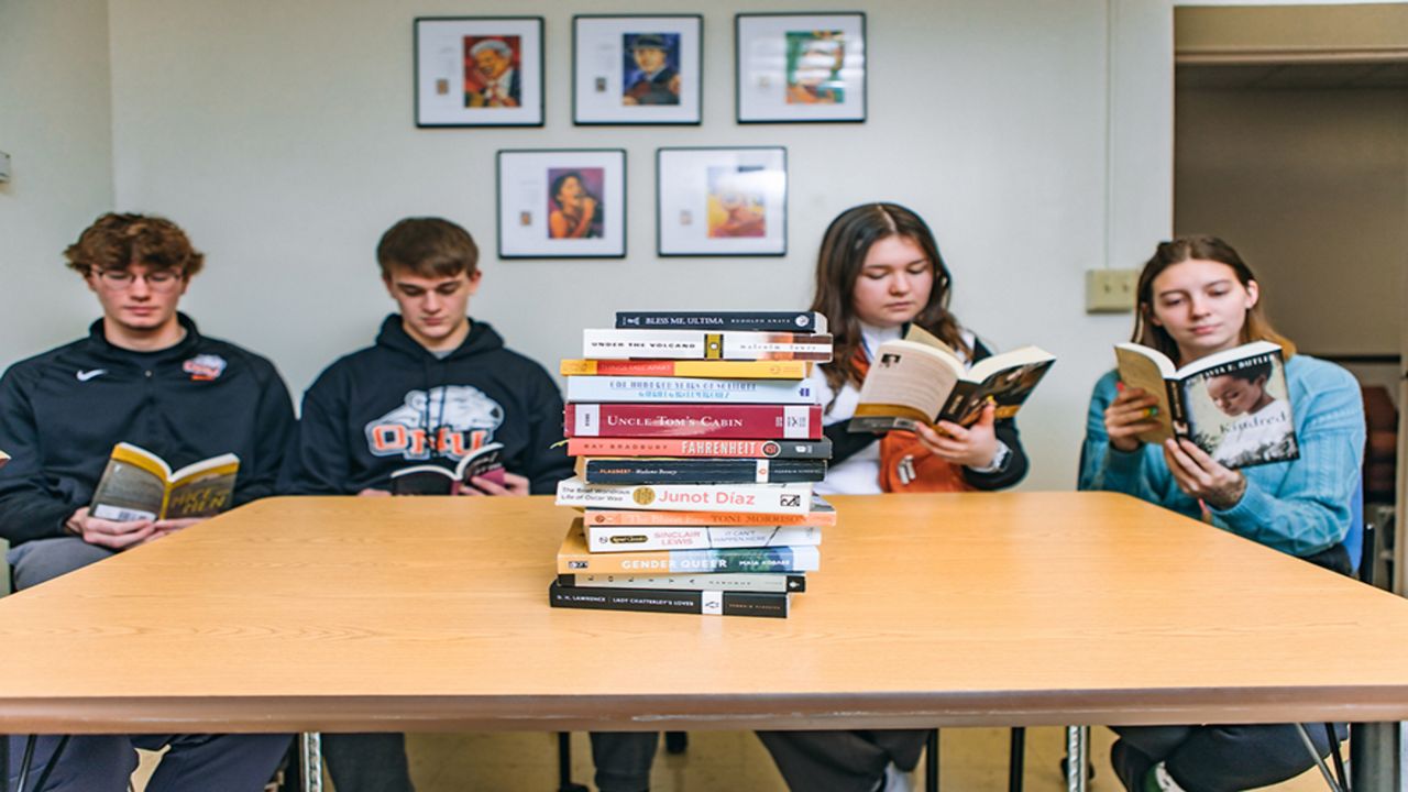 Students at a table look at books.