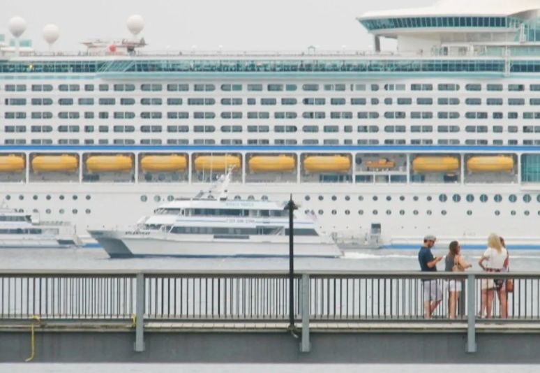 The cruise ship Adventure of the Seas rests in Frenchman Bay off downtown Bar Harbor on July 22, 2019 as a group of tourists stand on a pier and a whale watch boat glides by. Credit: Bill Trotter / BDN