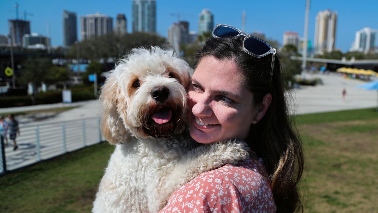 Rayellen Griffin, 48, gives her dog, Rembrandt, a lift while visiting the St. Pete Pier on Monday, Feb. 21, 2022 in St. Petersburg. Griffin moved to St. Pete from northern Kentucky last year. (Tampa Bay Times/Dirk Shadd)