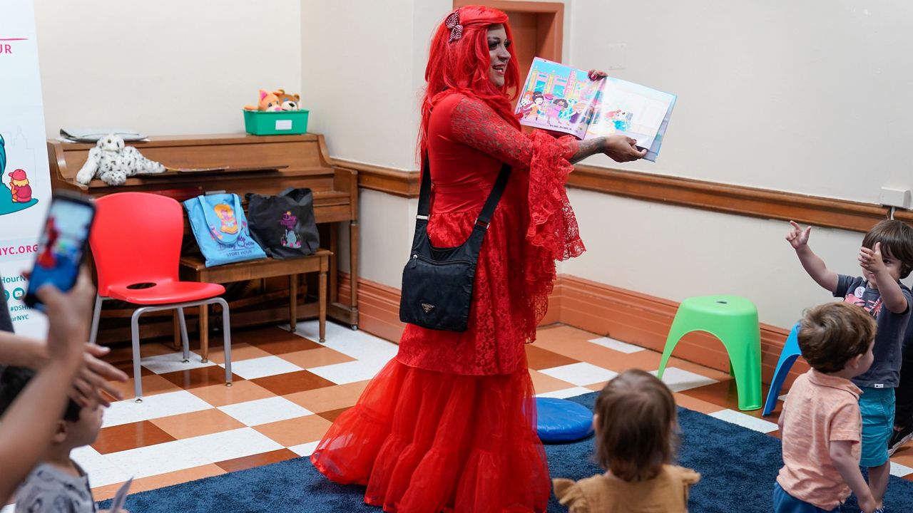  drag queen who goes by the name Flame reads stories to children and their caretakers during a Drag Story Hour at a public library in New York, Friday, June 17, 2022. (AP Photo/Seth Wenig)