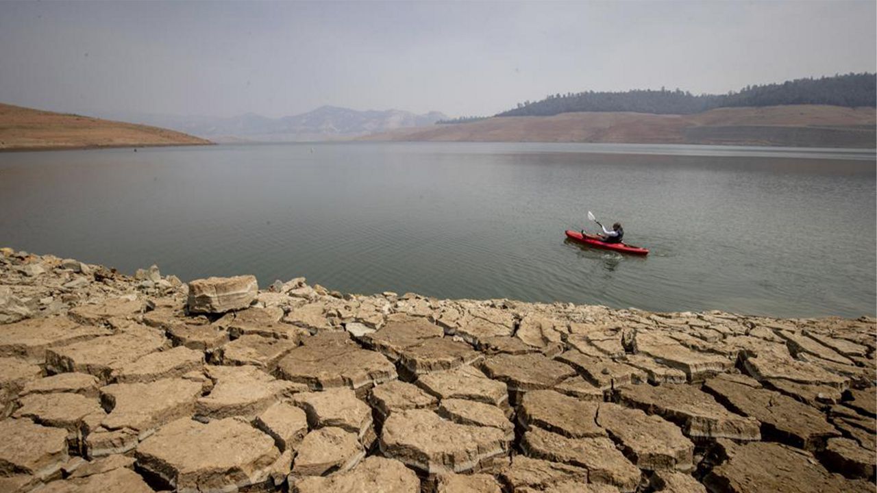In this Aug. 22, 2021, file photo a kayaker fishes in Lake Oroville as water levels remain low due to continuing drought conditions in Oroville, Calif. (AP Photo/Ethan Swope, File)