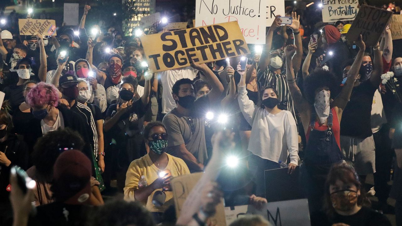 Demonstrators use their phone lights Wednesday, June 3, 2020 in downtown Los Angeles during a protest over the death of George Floyd who died May 25 after he was restrained by Minneapolis police. (AP Photo/Marcio Jose Sanchez)