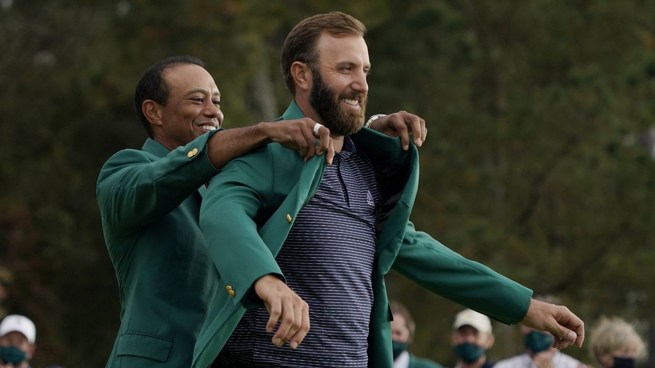 Tiger Woods helps Masters champion Dustin Johnson with his green jacket after his victory Sunday in Augusta, Ga. (AP Photo/Charlie Riedel)