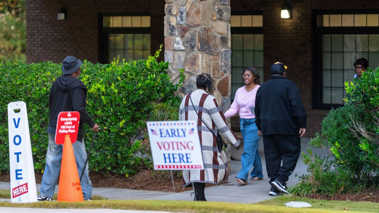 Voters are seen entering and exiting the polling station, Thursday, Oct. 31, 2024, in Stockbridge, Ga. (AP Photo/Jason Allen)