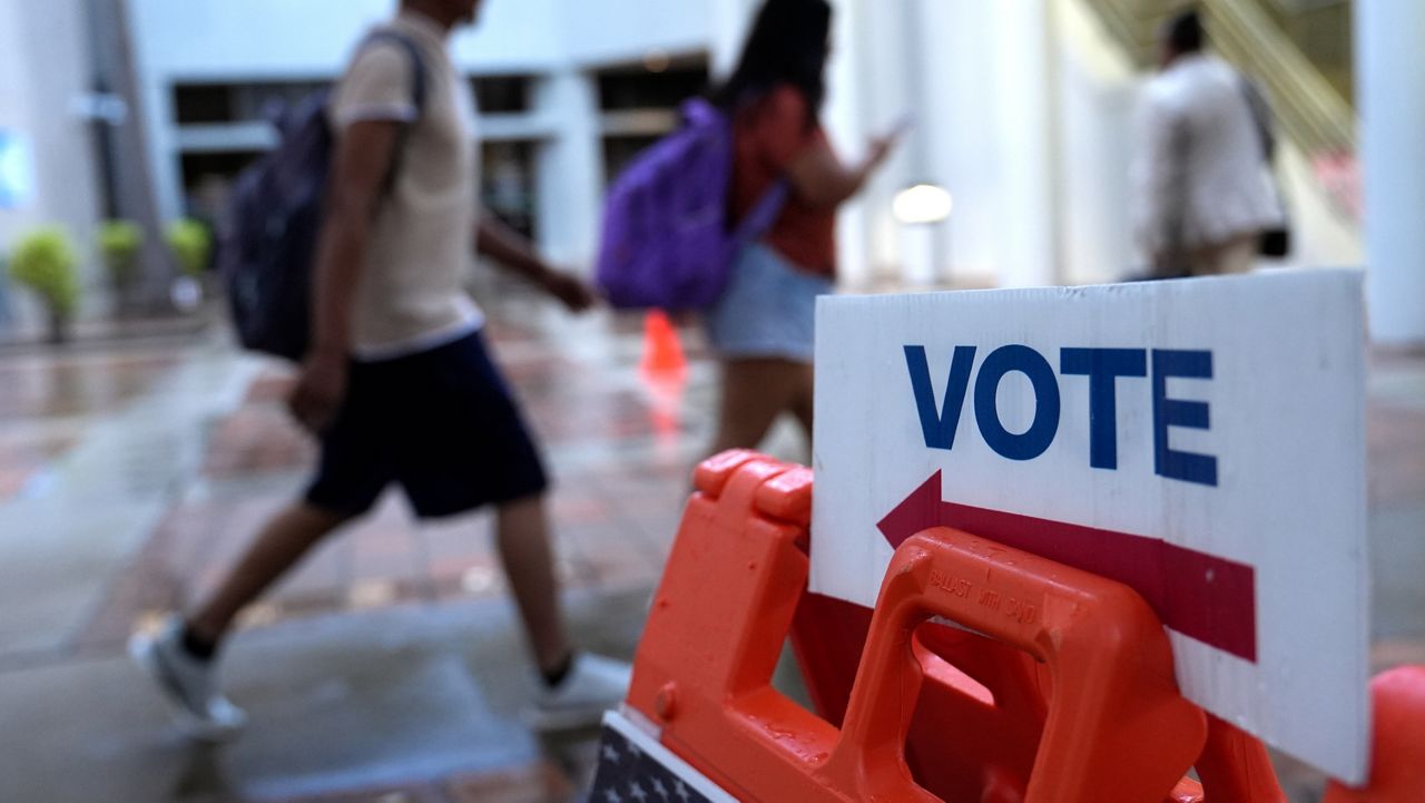 People walk past a Vote sign on the first day of early voting in the general election Monday, Oct. 21, 2024, in Miami. (AP Photo/Lynne Sladky)