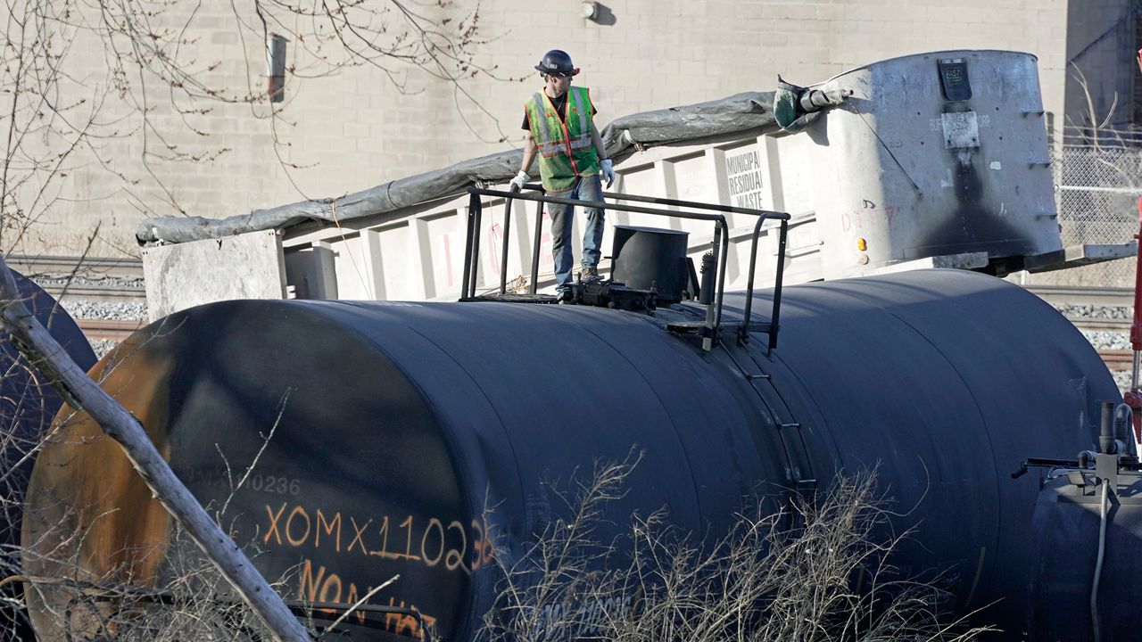 Person stands atop derailed train car