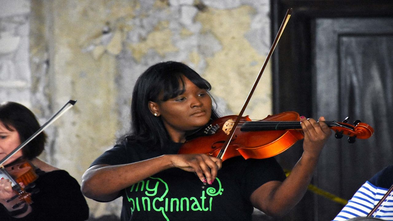 A violinist wearing a MYCincinnati t-shirt performs during an event at the Price Hill Will offices (Casey Weldon | Spectrum News 1)