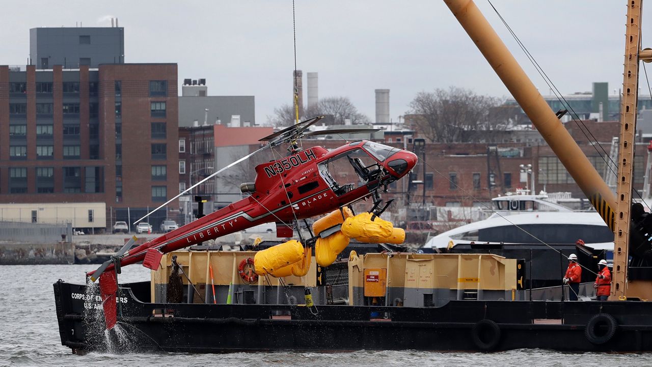 FILE - A helicopter is hoisted by crane from the East River onto a barge in New York on Monday, March 12, 2018. (AP Photo/Mark Lennihan, File)