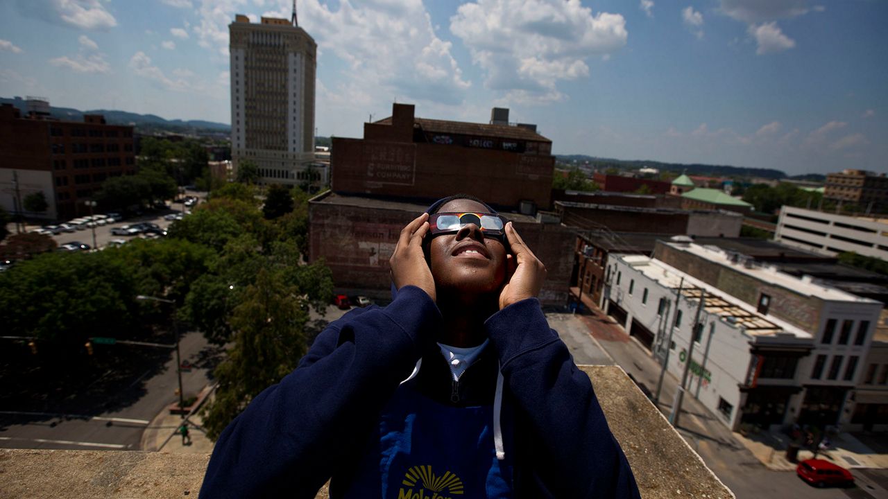 Justin Coleman, of Birmingham, Ala., holds his glasses up to his eyes as he watches the solar eclipse atop a parking structure, Monday, Aug. 21, 2017, in Birmingham. Safe solar eclipse glasses block out the sun’s ultraviolet rays and nearly all visible light. When worn indoors, only very bright lights should be faintly visible – not household furniture or wallpaper. (AP Photo/Brynn Anderson, File)