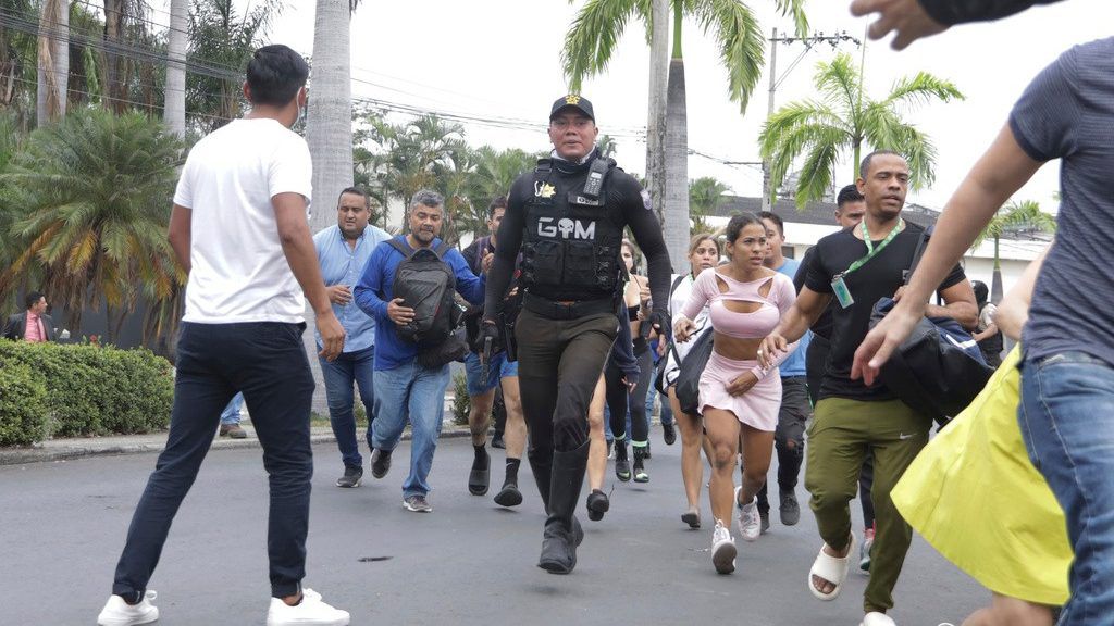 Police evacuate staff from the TC public television station after a group of armed men broke onto their set during a live broadcast, in Guayaquil, Ecuador, Tuesday, Jan. 9, 2024. The country has seen a series of attacks after the government imposed a state of emergency in the wake of the apparent escape of a powerful gang leader from prison. (AP Photo/Cesar Munoz)