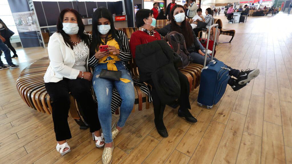 Personas con mascarillas esperan la llegada de sus familiares al Aeropuerto Internacional Mariscal Sucre de Quito. Archivo