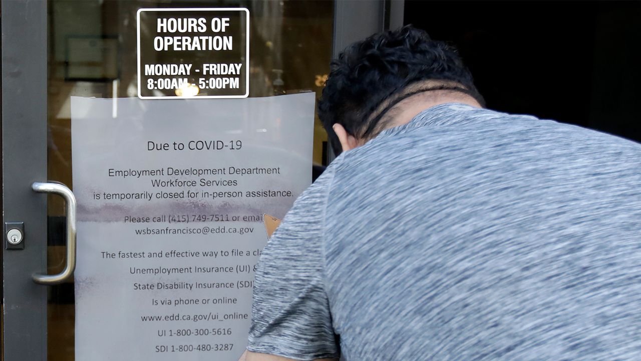  In this March 26, 2020 file photo a man takes a photo of a sign advising that the Employment Development Department is closed due to coronavirus concerns, in San Francisco. (AP Photo/Jeff Chiu, File)