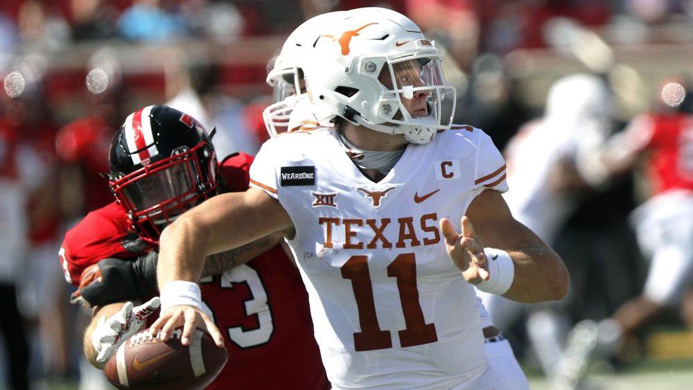 Texas quarterback Sam Ehlinger passes downfield under pressure from defensive lineman Eli Howard during the first half of an NCAA college football game against Texas Tech, Saturday Sept. 26, 2020, in Lubbock, Texas. (AP Photo/Mark Rogers)