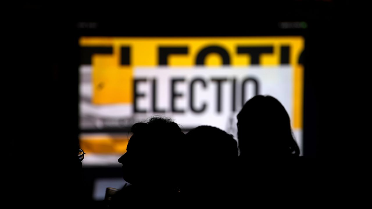 Voters monitor results during an election night watch party, Tuesday, Nov. 5, 2024, in Cincinnati. (AP Photo/Kareem Elgazzar)