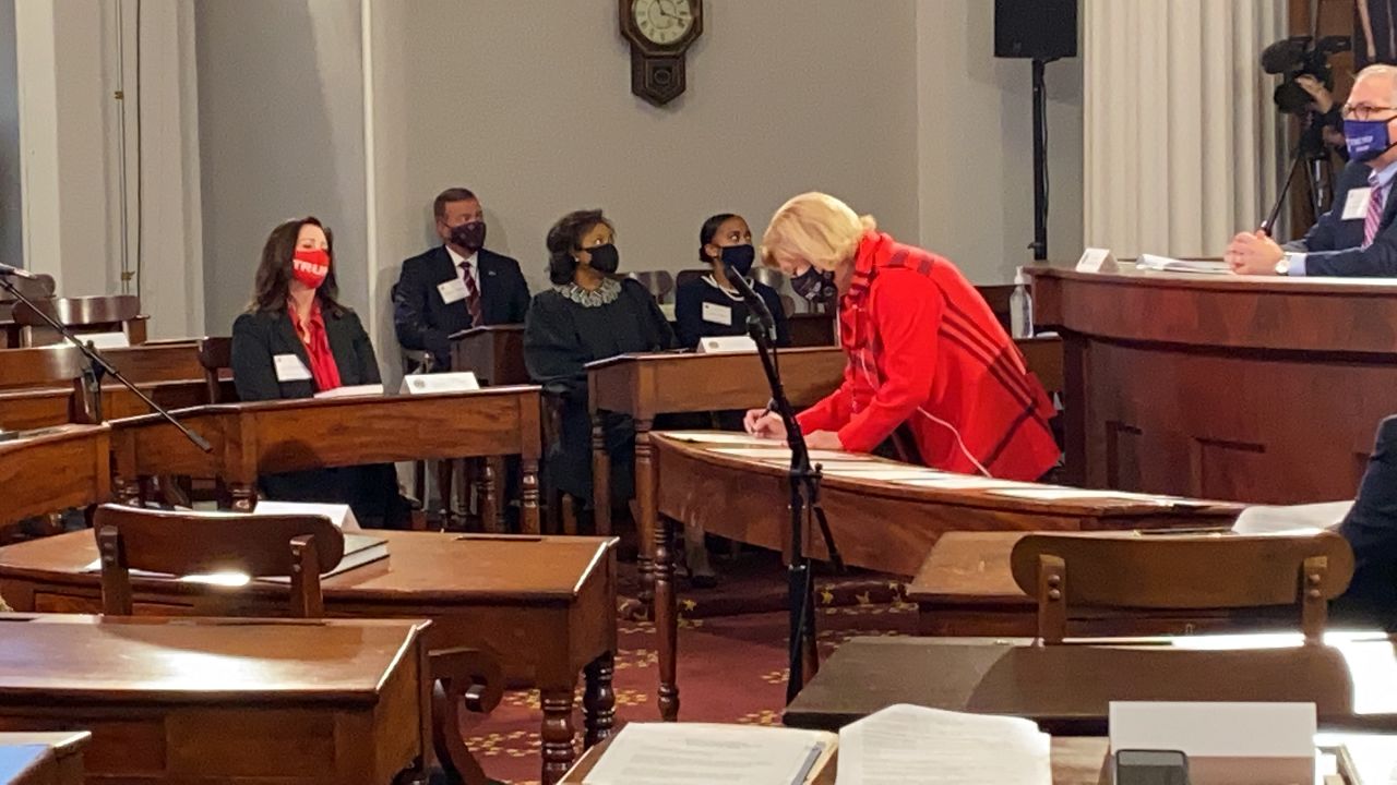 Susan Mills signs one of the certificates that will go to the Senate for opening Jan. 6. Mills cast her ballot as a presidential elector for the first time Monday.