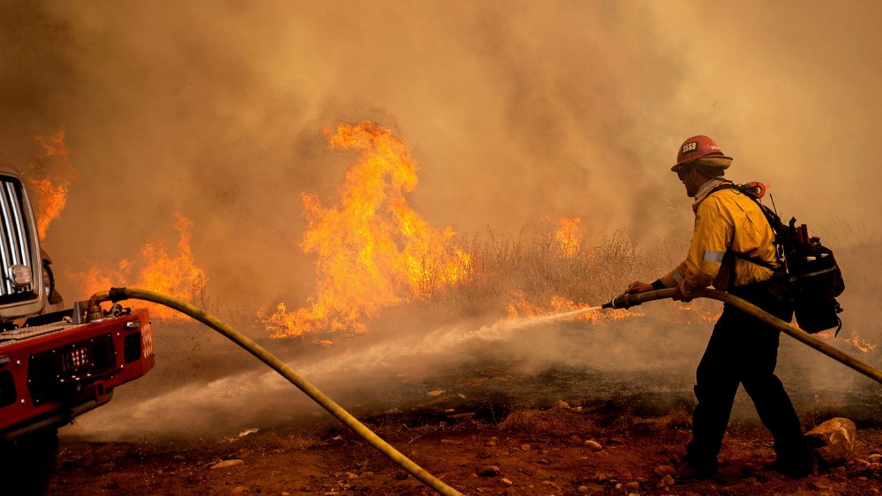 A helicopter drops water while battling the Electra Fire in the Pine Acres community of Amador County, Calif., on Tuesday, July 5, 2022. (AP Photo/Noah Berger)