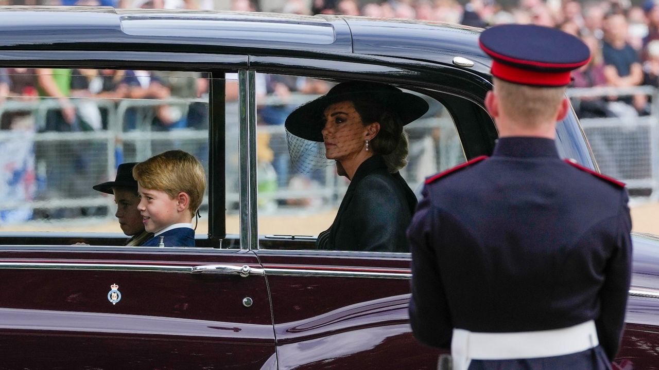 Kate, princess of Wales, and her children Prince George and Princess Charlotte ride in a car behind the coffin of Queen Elizabeth II as it is pulled on a gun carriage through the streets of London following her funeral service. (AP Photo/Kin Cheung,Pool)