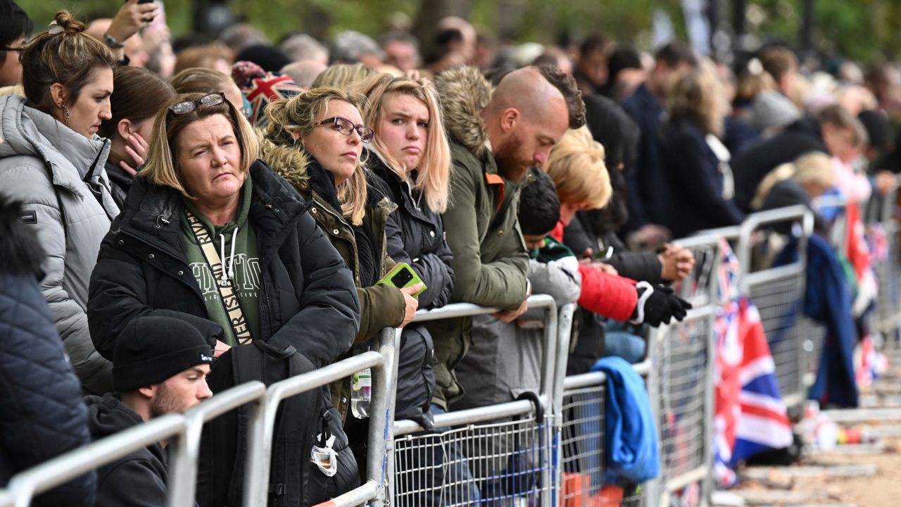 Members of the public wait for the passage of the coffin along the procession route during the state funeral service of Queen Elizabeth II. (Paul Ellis/Pool Photo via AP)