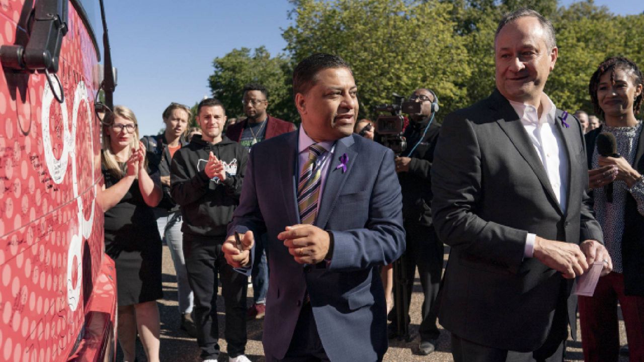 Courtney Allen, far left, and Joseph Green, both organizers for Mobilize Recovery, applaud as Douglas Emhoff, husband of Vice President Kamala Harris, right, and Dr. Rahul Gupta, Director of National Drug Control Policy, second from right, sign the Mobilize Recovery bus parked Pennsylvania Avenue in front of the White House in Washington, Friday, Sept. 23, 2022. (AP Photo/Carolyn Kaster)