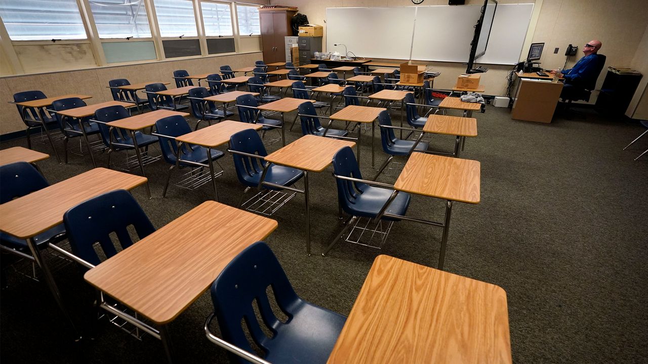 In this Aug. 18, 2020 file photo, math teacher Doug Walters sits among empty desks as he takes part in a video conference with other teachers to prepare for at-home learning at Twentynine Palms Junior High School in Twentynine Palms, Calif. (AP Photo/Gregory Bull, File)