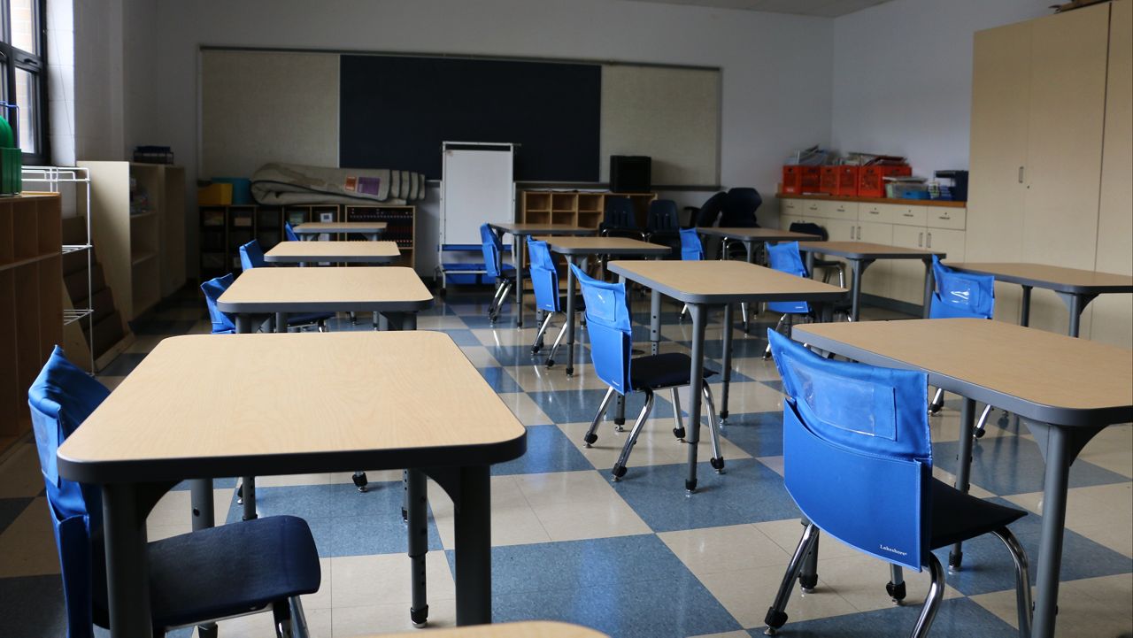 FILE - In this Aug. 18, 2020 file photo, math teacher Doug Walters sits among empty desks as he takes part in a video conference with other teachers to prepare for at-home learning at Twentynine Palms Junior High School in Twentynine Palms, Calif. Most of California's 6 million public school students have not seen the inside of a classroom in 10 months. Gov. Gavin Newsom is hoping his $2 billion plan to resume in-person classes will get schools to reopen quickly. (AP Photo/Gregory Bull, File)