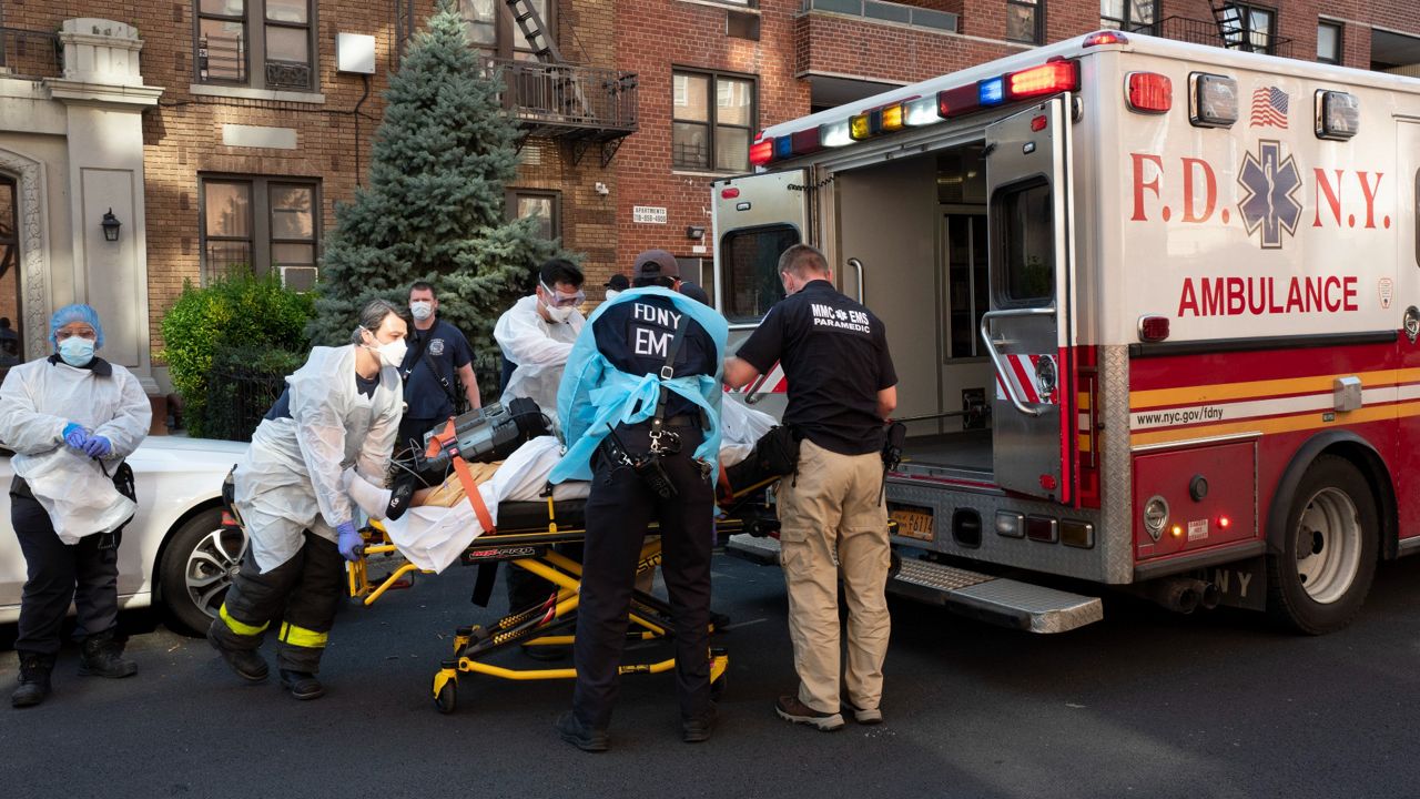 EMTs move a man on a stretcher into an ambulance on a street in Brooklyn.