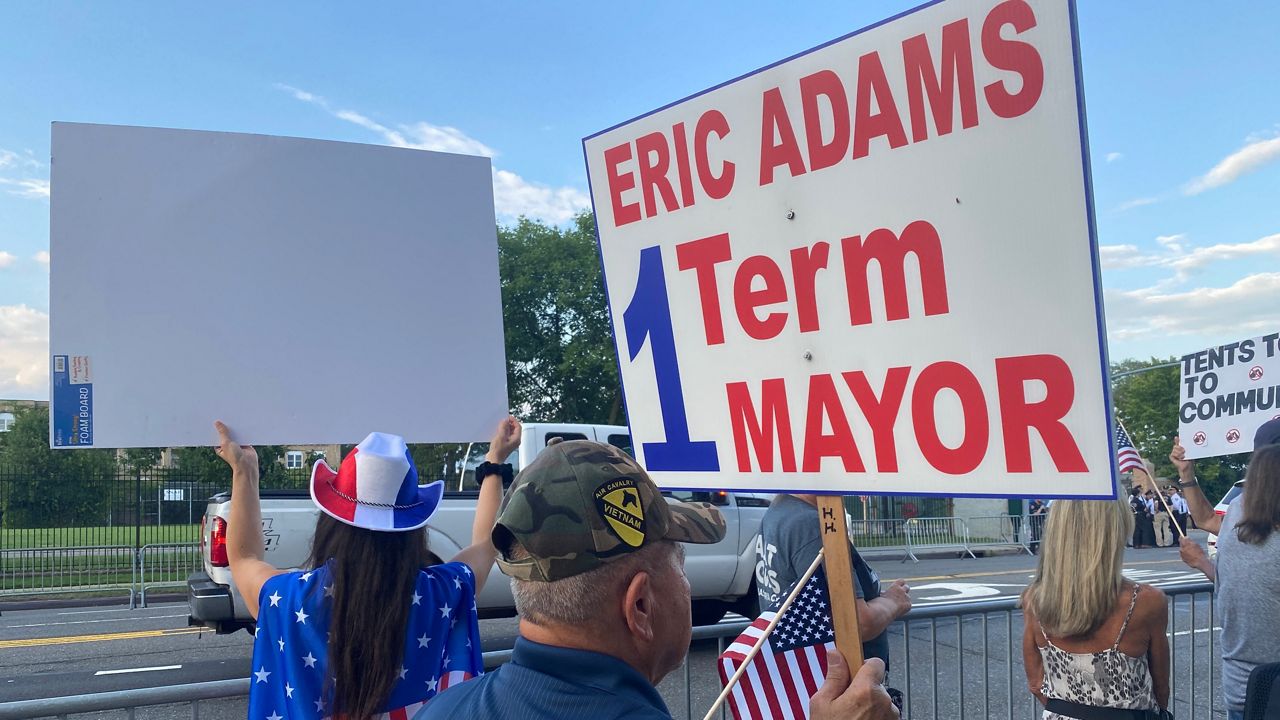 A man holds up a sign protesting Mayor Eric Adams.