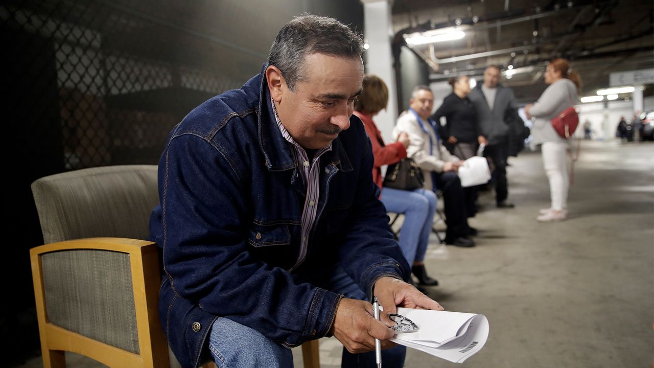 Unionized hospitality workers, including Luis Estrada, at left, wait in line in a basement garage to apply for unemployment benefits at the Hospitality Training Academy Friday, March 13, 2020, in Los Angeles. Fearing a widespread health crisis, Californians moved broadly Friday to get in front of the spread of the coronavirus, shuttering schools that educate hundreds of thousands of students, urging the faithful to watch religious services online and postponing or scratching just about any event that could attract a big crowd.(AP Photo/Marcio Jose Sanchez)