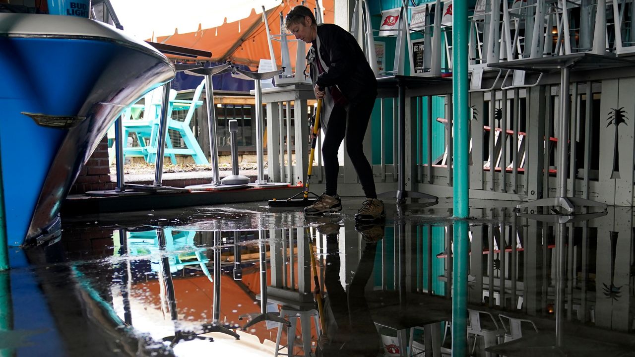Kate Connell sweeps water and mud from the floor at Salty's Gulfport bar and in the aftermath of Tropical Storm Eta, Thursday, Nov. 12, 2020, in Gulfport, Fla. (Lynne Sladky/AP)