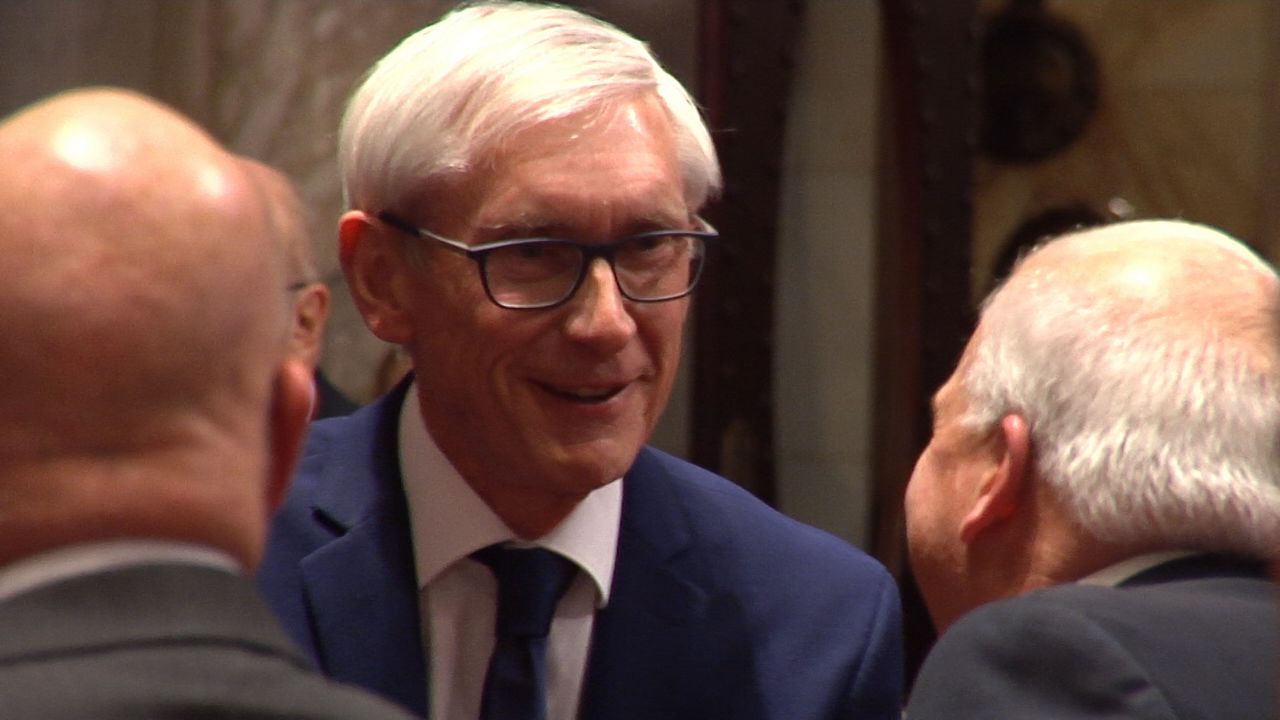 Gov. Tony Evers shakes hands with lawmakers in Assembly chamber.