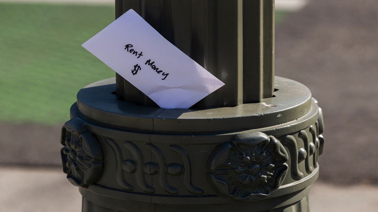 A paper envelope written with the words "Rent Money $ " is left tucked in a lighting pole in the Boyle Heights east district of Los Angeles on April 1, 2020. (AP Photo/Damian Dovarganes)