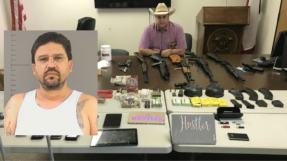 Caldwell County Sheriff Daniel C. Law poses with drugs, weapons and other materials seized at a Maxwell, Texas, home. Inset: Booking photo of suspect Adam Gonzales. (Caldwell County Sheriff's Office)