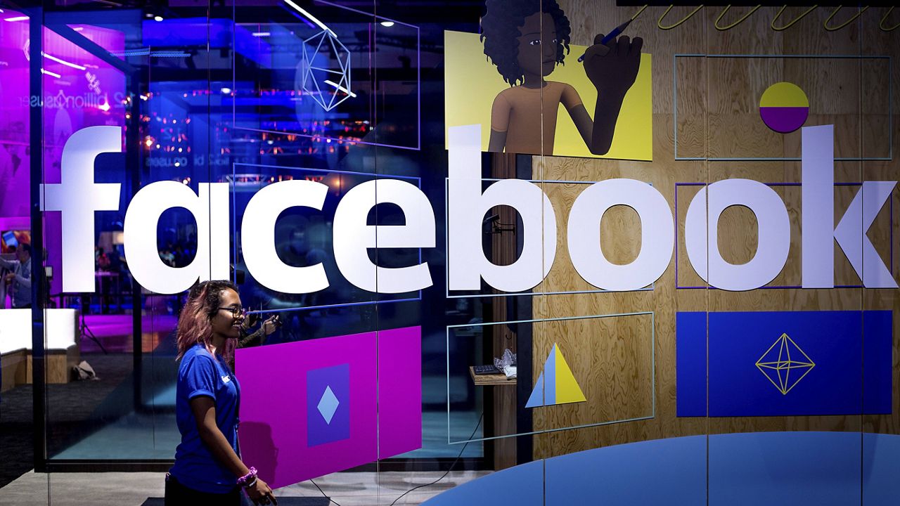 A conference worker passes a demo booth at Facebook's annual F8 developer conference, in San Jose, Calif., on April 18, 2017. (AP Photo/Noah Berger, File)