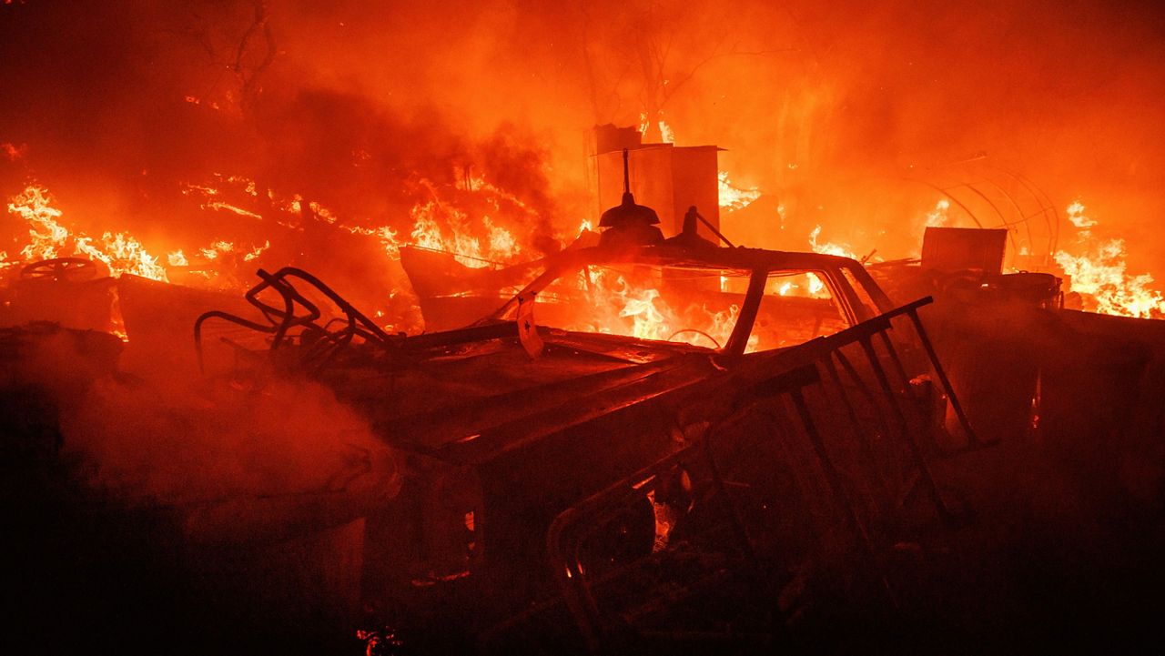 A vehicle burns Monday at a property ravaged from the Fairview Fire near Hemet, Calif. (AP Photo/Ethan Swope)