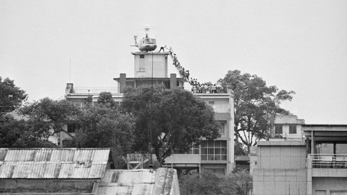 A CIA employee helps Vietnamese evacuees onto a helicopter half a mile from the U.S. Embassy in Saigon in 1975. (Bettmann Archive via Getty)