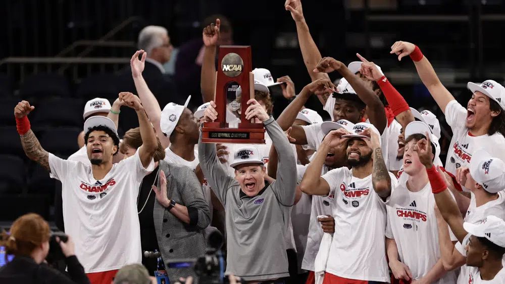 Florida Atlantic head coach Dusty May holds up the trophy as Florida Atlantic players celebrate after defeating Kansas State in the second half of an Elite 8 college basketball game in the NCAA Tournament's East Region final, Saturday, March 25, 2023, in New York. (AP Photo/Adam Hunger)