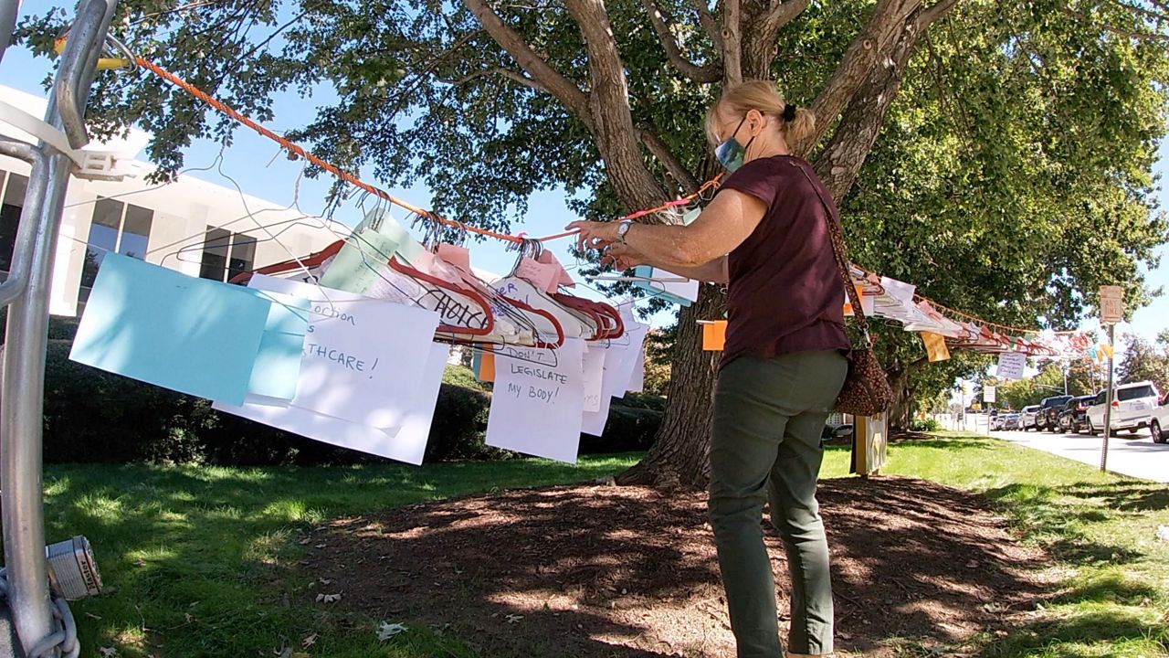 Charlotte Women's Movement member Diane Stevens puts up hangers they collected outside the North Carolina General Assembly in Raleigh.