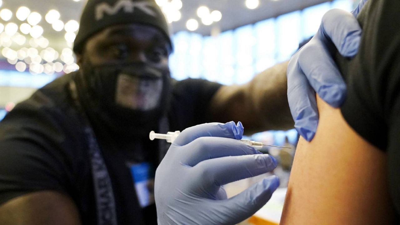 FILE - DeMarcus Hicks, a recent graduate of nursing school who is working as a contractor with the Federal Emergency Management Agency, gives a person a Pfizer COVID-19 vaccine booster shot, Dec. 20, 2021, on the first day of a COVID-19 vaccination clinic in Federal Way, Wash. (AP Photo/Ted S. Warren, File)