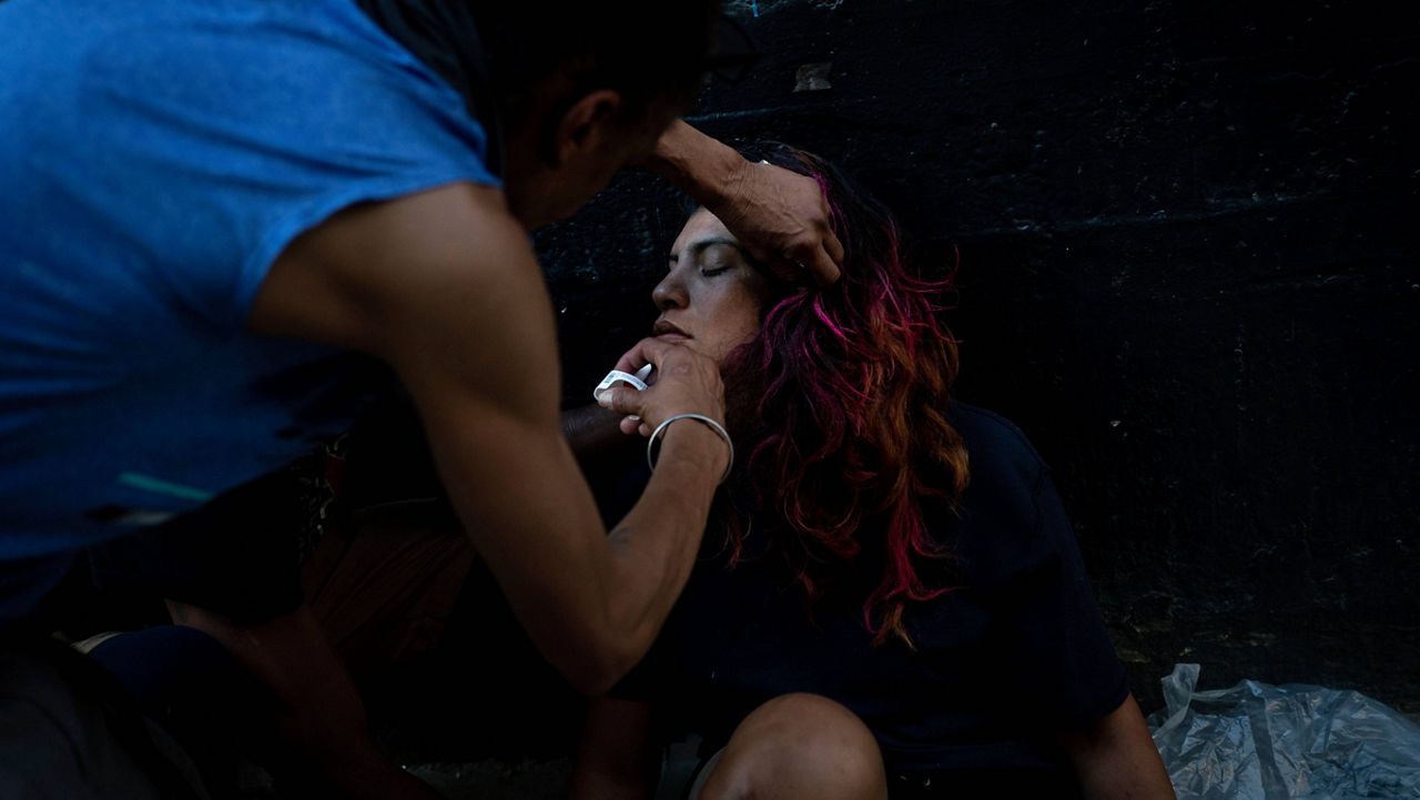  homeless man injects a Narcan nasal spray into the nose of a female addict who appears to be overdosed in Los Angeles, Thursday, Aug. 25, 2022. For too many people strung out on the drug, the sleep that follows a fentanyl hit is permanent. The highly addictive and potentially lethal drug has become a scourge across America and is taking a toll on the growing number of people living on the streets of Los Angeles. (AP Photo/Jae C. Hong)