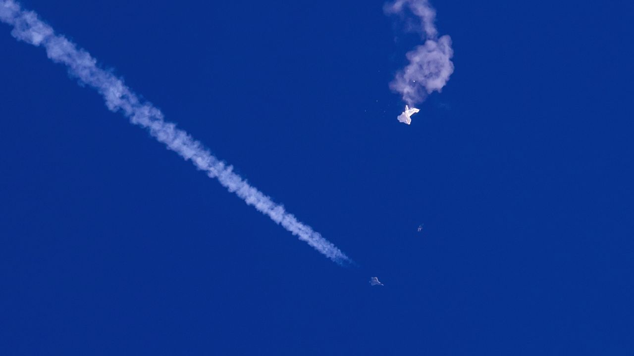 In this photo provided by Chad Fish, the remnants of a large balloon drift above the Atlantic Ocean on Saturday, just off the coast of South Carolina, with a fighter jet and its contrail seen below it. (Chad Fish via AP)