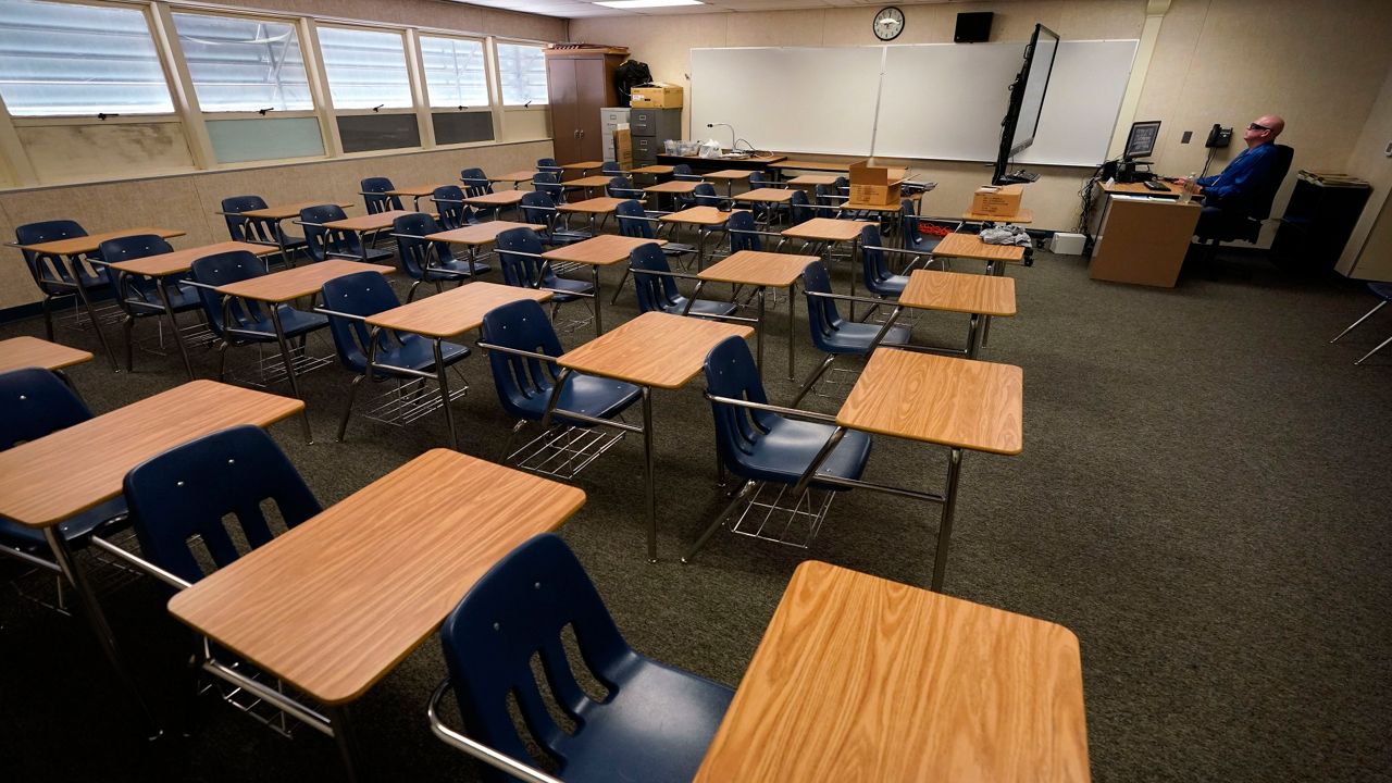 Image of an empty classroom with a teacher at a podium (AP Image/File)