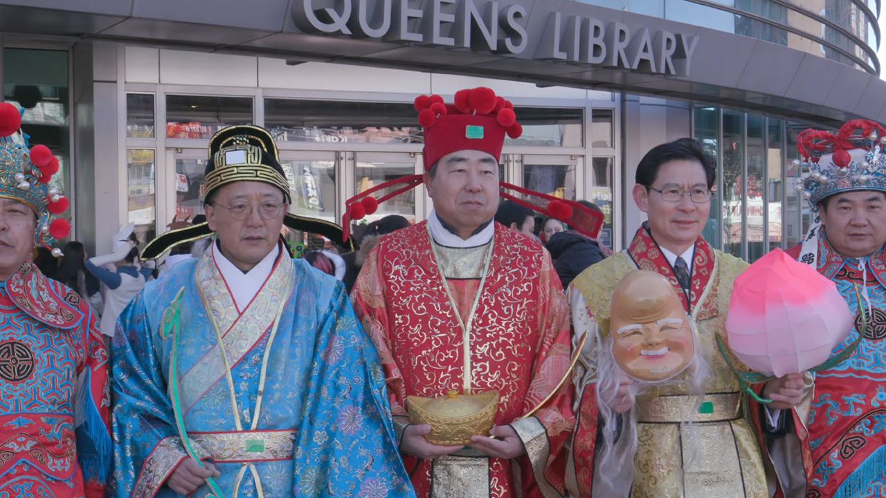 A group of people wear blue, red, and bronze outfits for Lunar New Year.