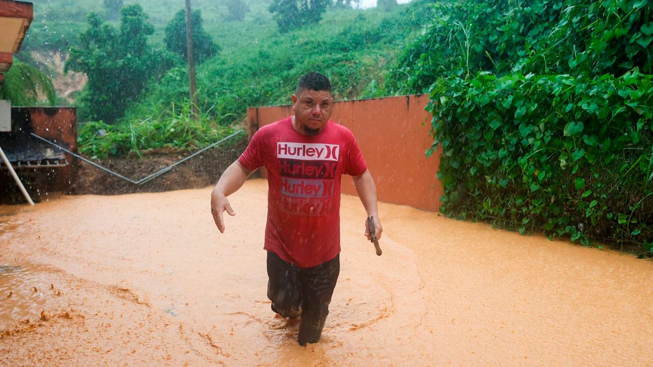 A man walks on a road flooded by Hurricane Fiona in Cayey, Puerto Rico, on Sunday, Sept. 18, 2022. (AP Photo/Stephanie Rojas)