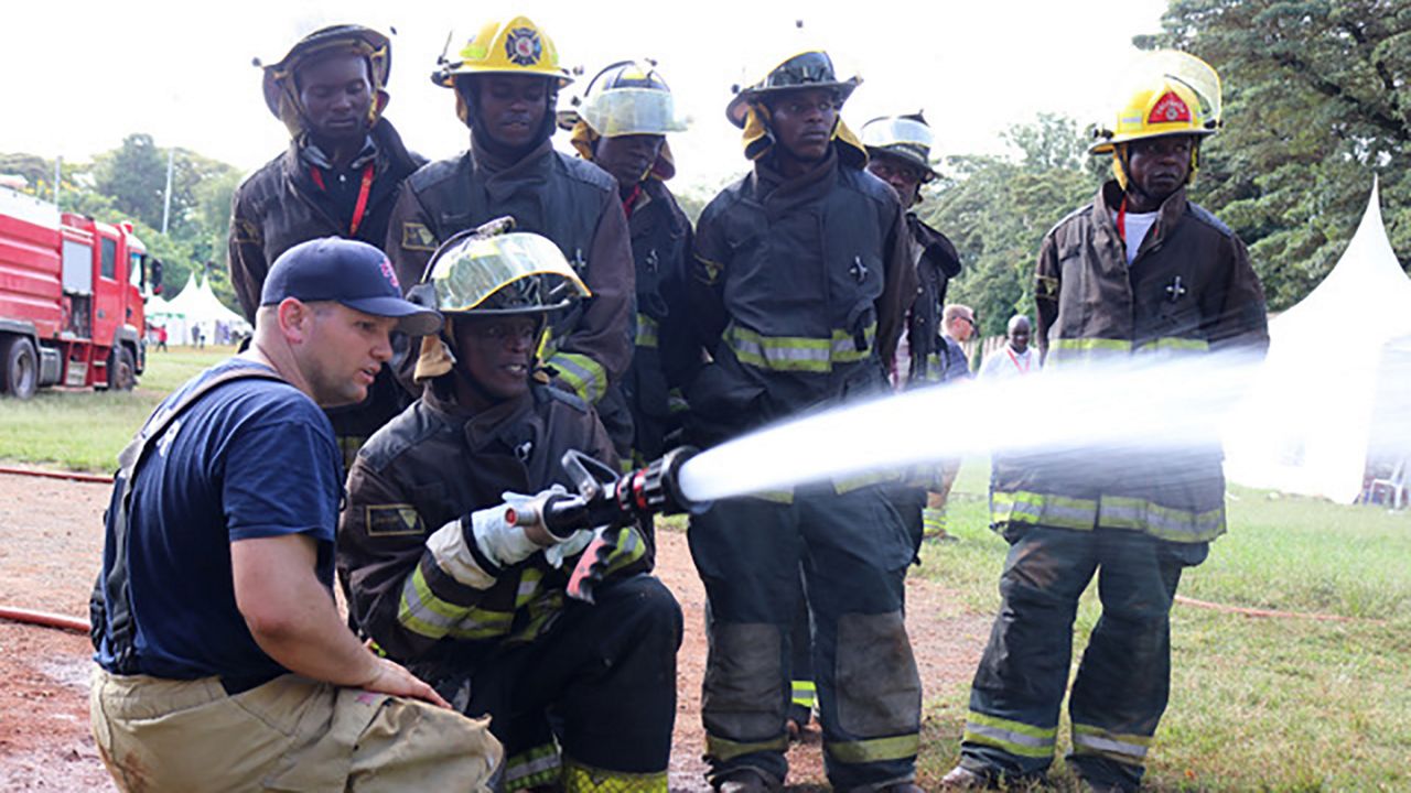 US firefighter watches as team of African firefighters practice work with a fire hose