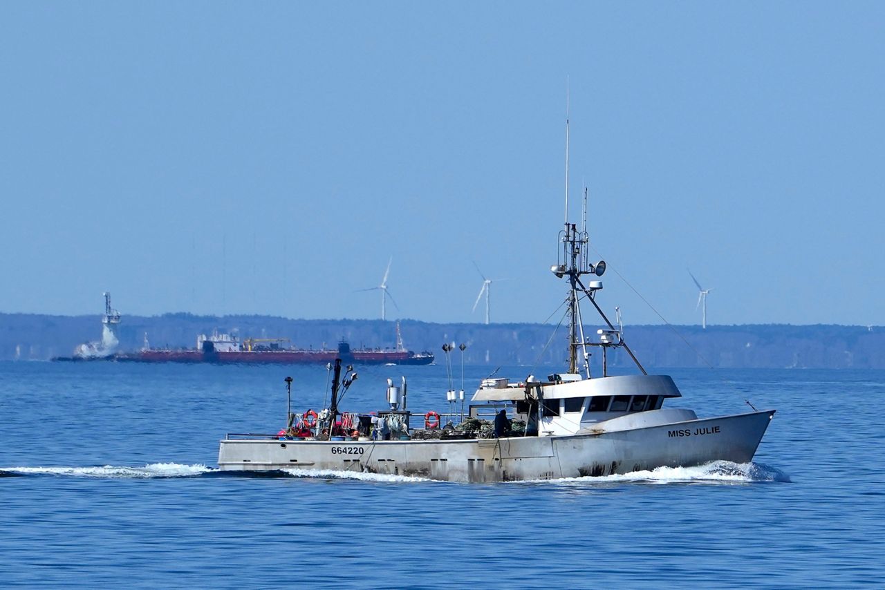 A fishing boat, foreground, and commercial ship travel across Cape Cod Bay, Monday, March 27, in Massachusetts. Vessels are restricted in how fast they can travel and how commercial fishermen can fish in an effort to protect right whales from boat strikes and rope entanglements. The drive to protect vanishing whales has brought profound impacts to marine industries, and those changes are accelerating as the Endangered Species Act approaches its 50th anniversary. (AP Photo/Robert F. Bukaty)