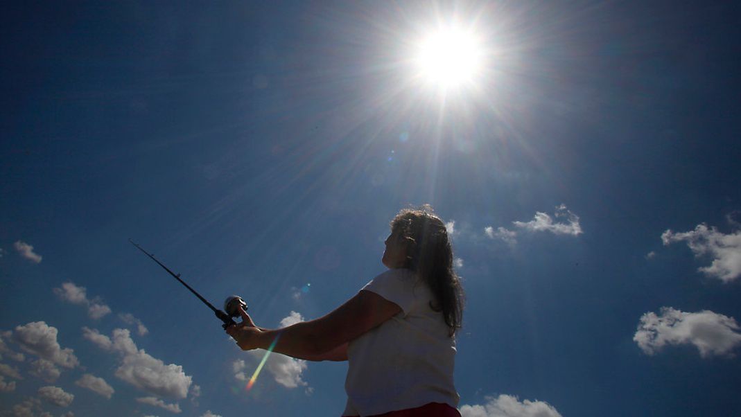 A woman fishing under a sunny sky