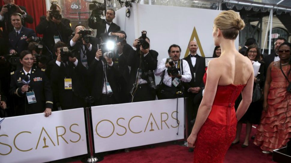 In this Feb. 22, 2015 file photo, actress Rosamund Pike arrives at the Oscars in Los Angeles. There are two paths on the Oscars red carpet: one for the famous people, and one for everyone else. Stanchions and velvet ropes separate the recognizable from the not. (Photo by Matt Sayles/Invision/AP, File)
