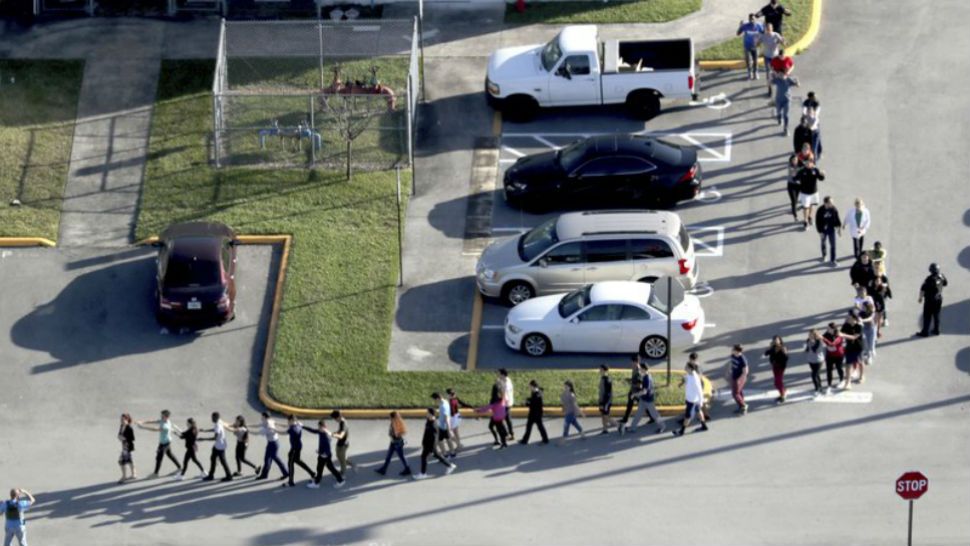 Students are evacuated by police from Marjory Stoneman Douglas High School in Parkland, Fla., on Wednesday, Feb. 14, 2018, after a shooter opened fire on campus. (AP Photo/Mike Stocker)